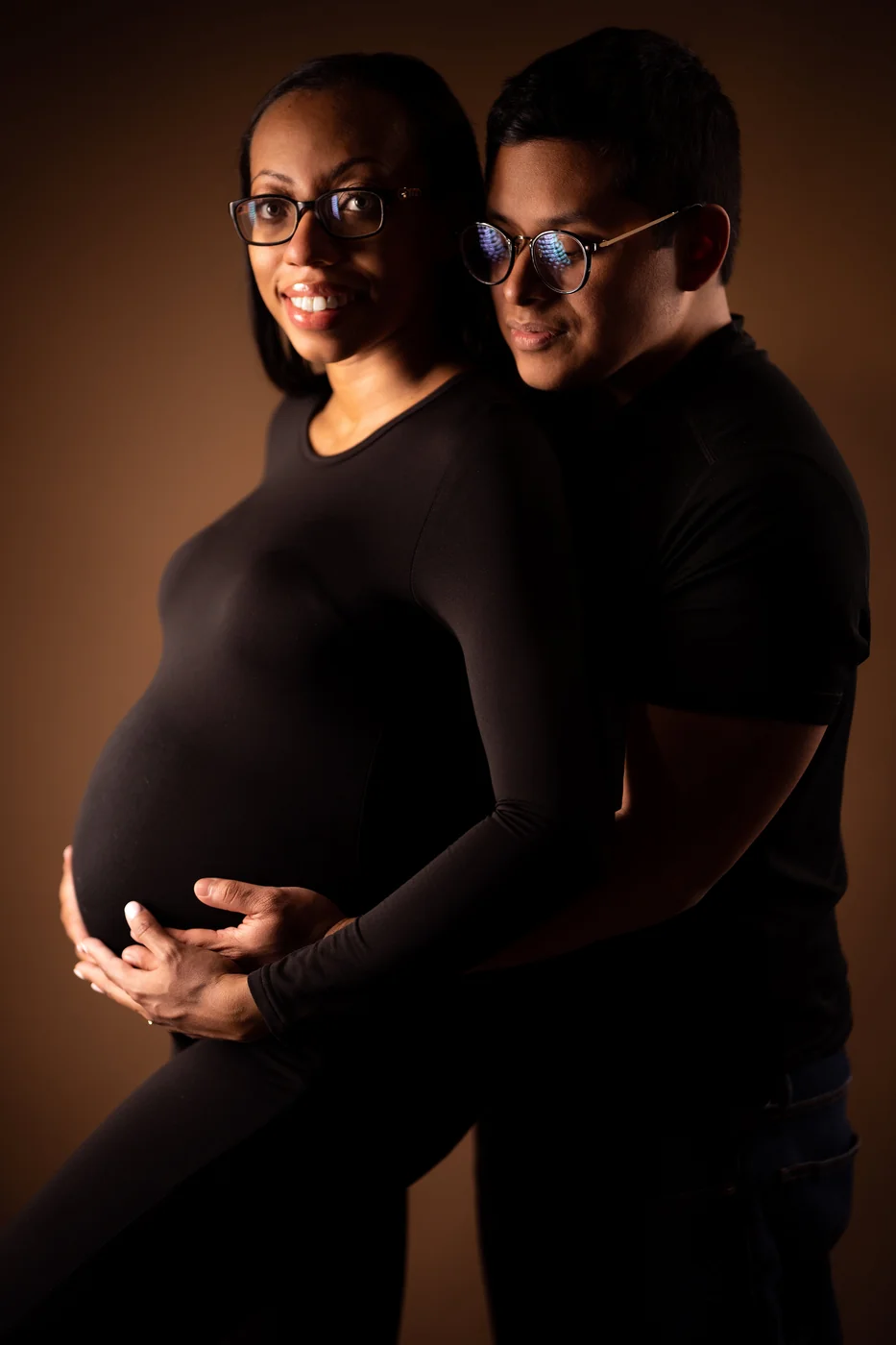 Luis and Jacqui together in a low-lit maternity portrait