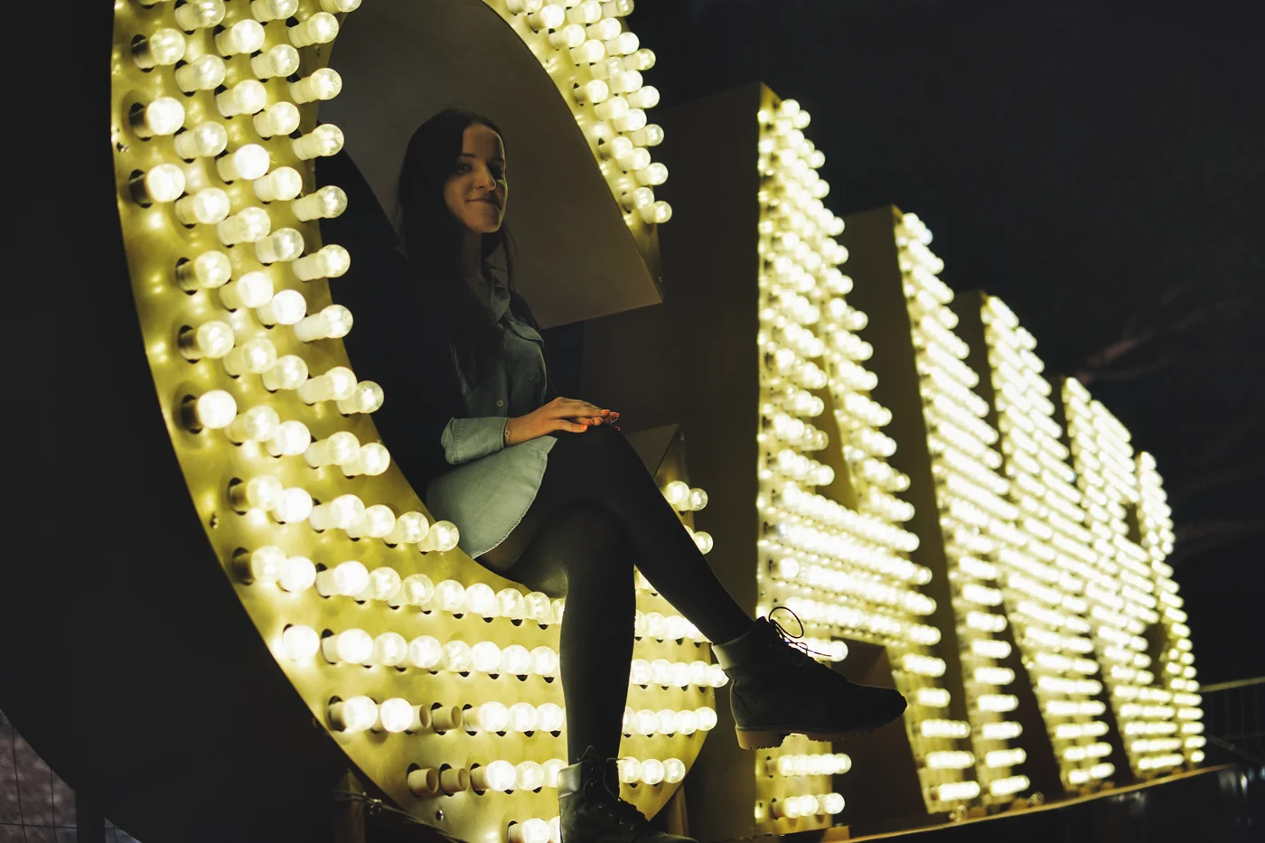 A woman sitting inside a giant lit letter